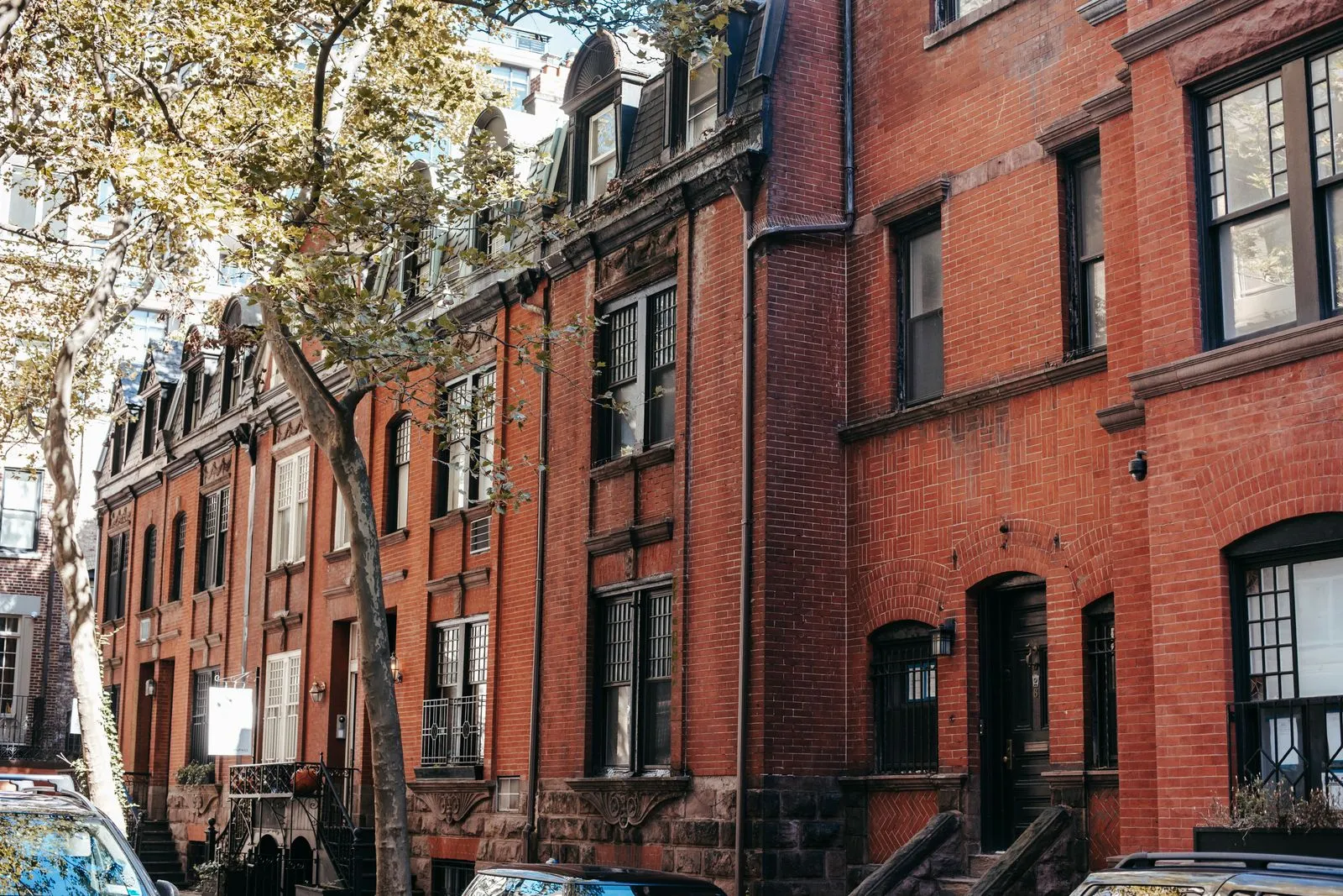 Exterior of aged brick residential building with windows and stairs located on city street on sunny autumn day